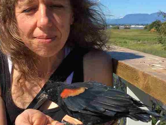 Larissa at a bird sanctuary, with bird eating out of her hand